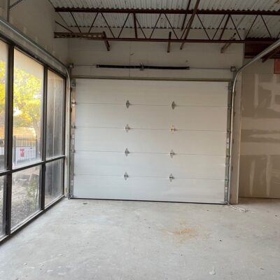 A large white sectional Amarr 2743 garage door installed in a spacious commercial building.