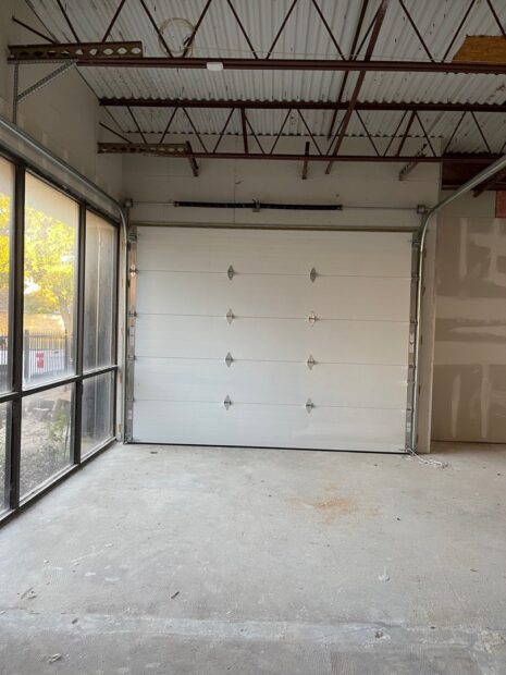 A large white sectional Amarr 2743 garage door installed in a spacious commercial building.