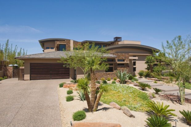 House exterior with a driveway, plants, trees and a path