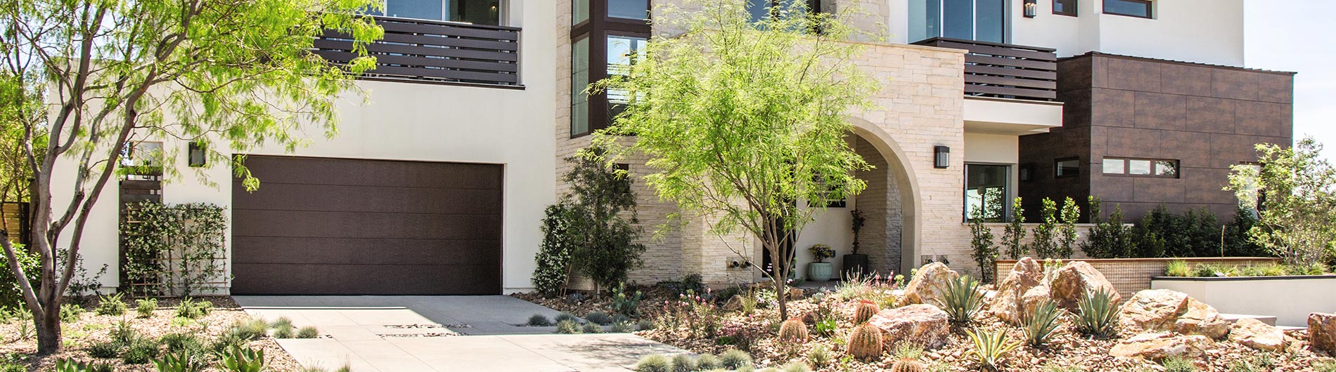 Modern home exterior with a sleek dark garage door, desert landscaping, and contemporary architectural design.