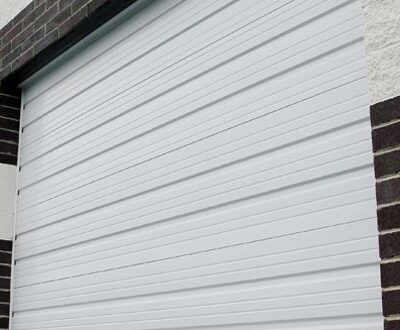 A white commercial roll-up door with horizontal grooves, partially open on a brick building.