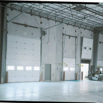 Interior view of a large industrial warehouse featuring multiple Amarr 2432 overhead garage doors.