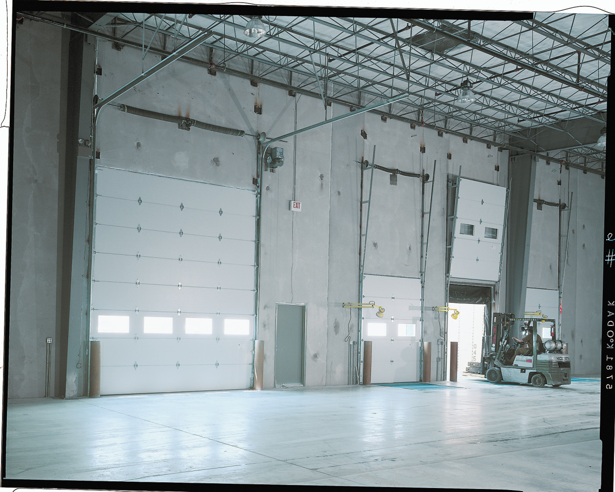 Interior view of a large industrial warehouse featuring multiple Amarr 2432 overhead garage doors.