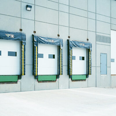 Exterior view of a modern industrial building with three Amarr 2432 garage doors.