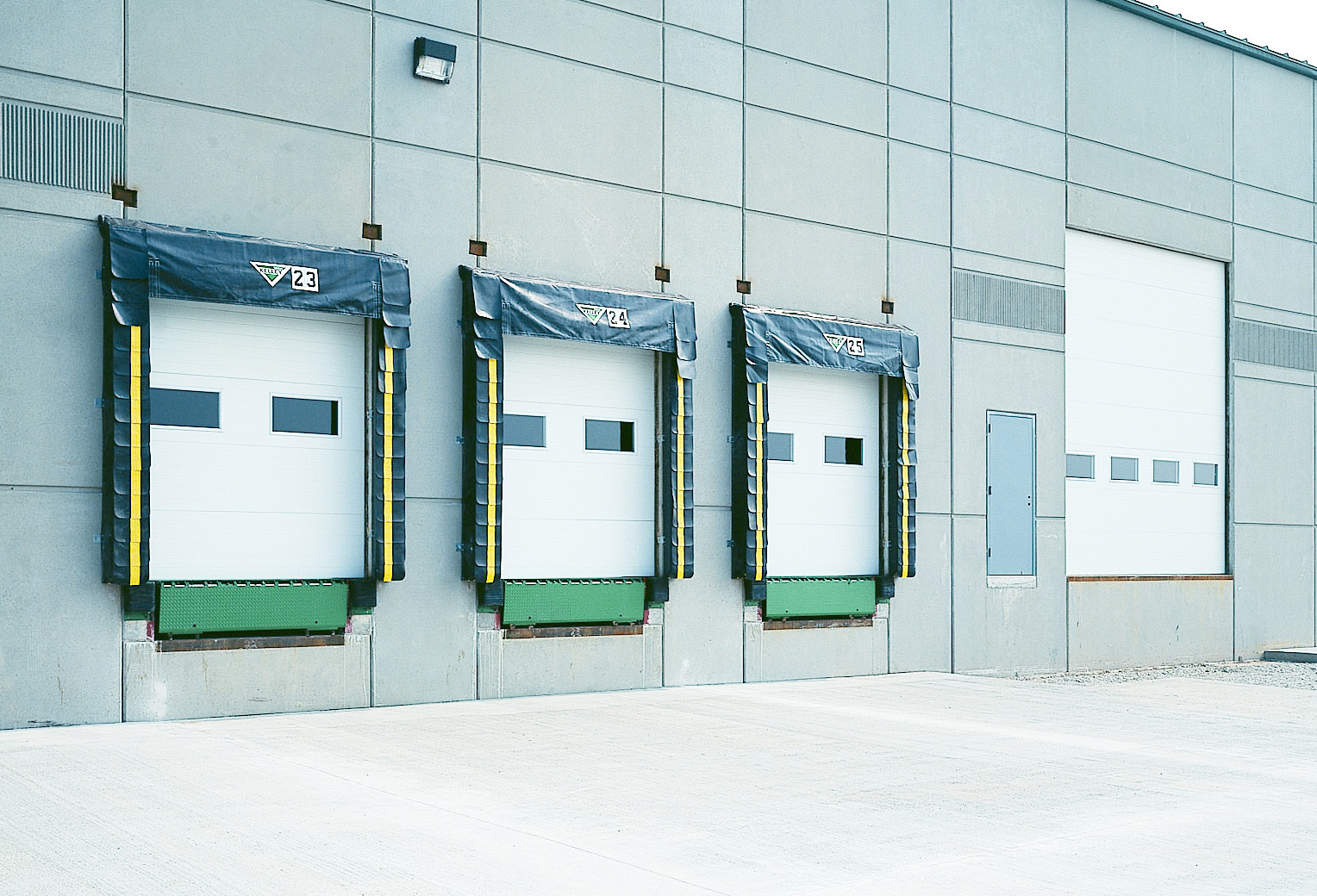 Exterior view of a modern industrial building with three Amarr 2432 garage doors.