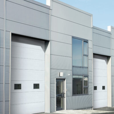 A modern industrial building featuring sleek, light gray Amarr 2731 garage doors.