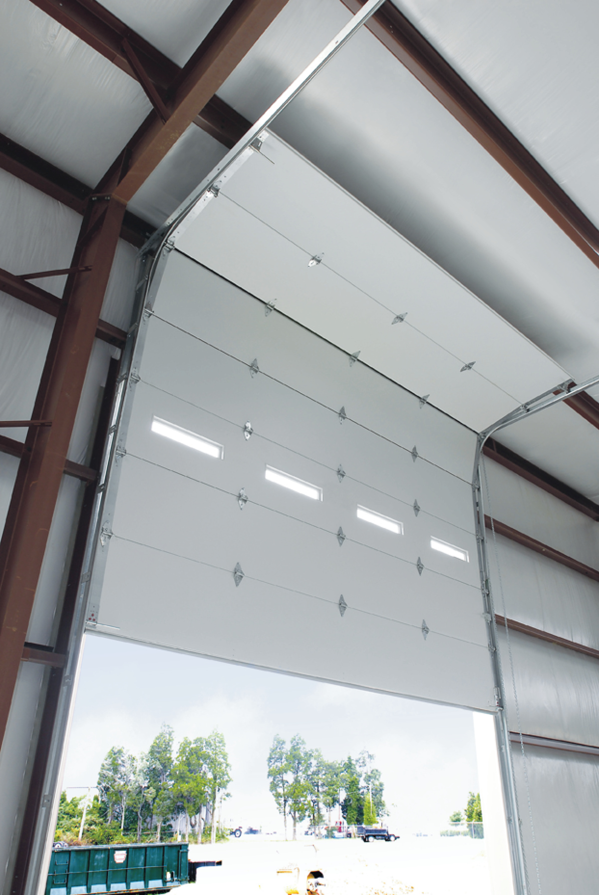 Interior perspective of an industrial building featuring a partially open Amarr 2731 garage door