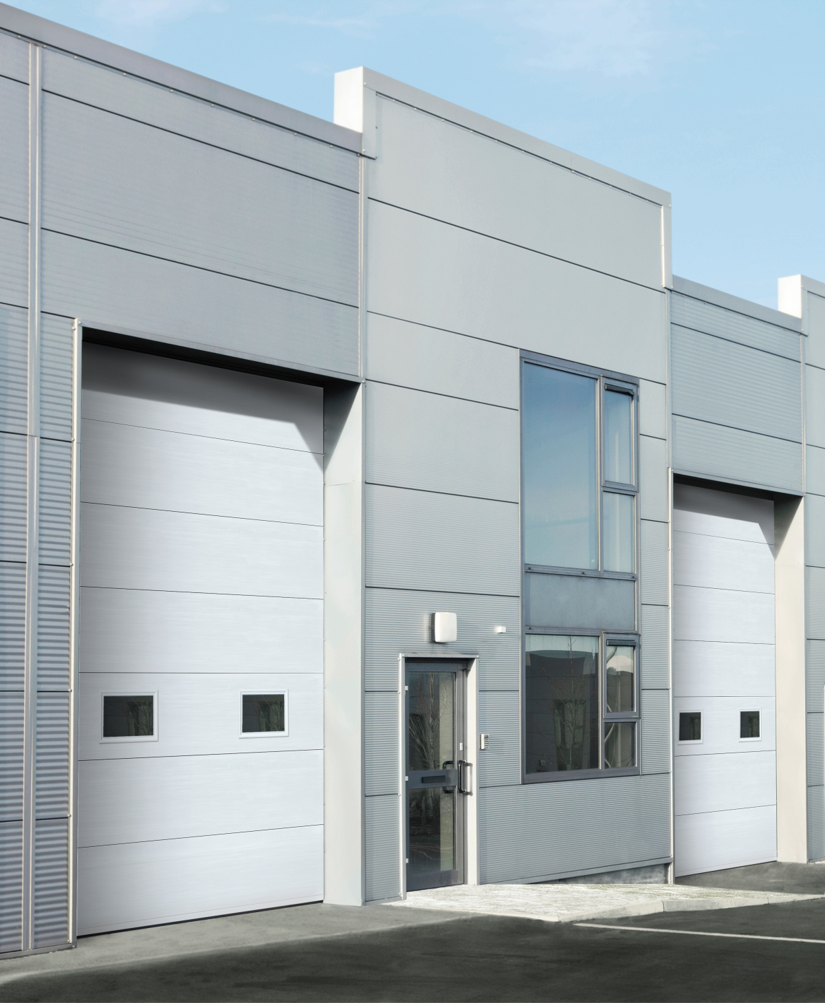 A modern industrial building featuring sleek, light gray Amarr 2731 garage doors.