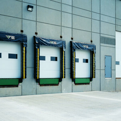 A clear exterior shot of an industrial building showing three white Amarr 2732 garage doors