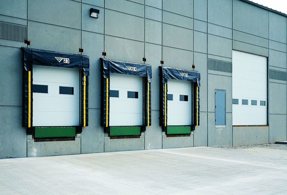 A clear exterior shot of an industrial building showing three white Amarr 2732 garage doors