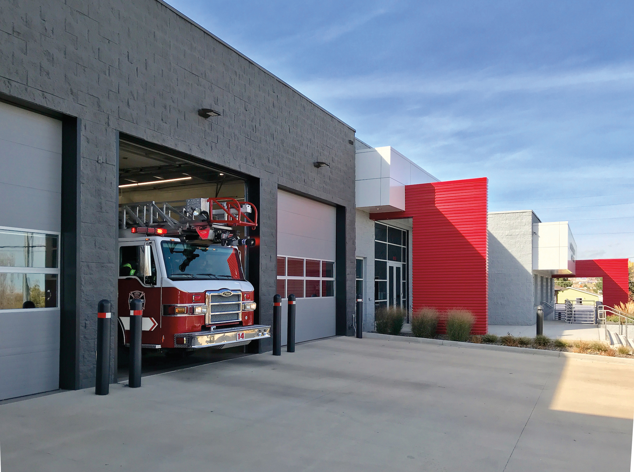 A fire station with multiple open bays with large gray Amarr 2742 overhead doors.