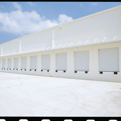 A long white commercial building with a row of multiple loading docks.