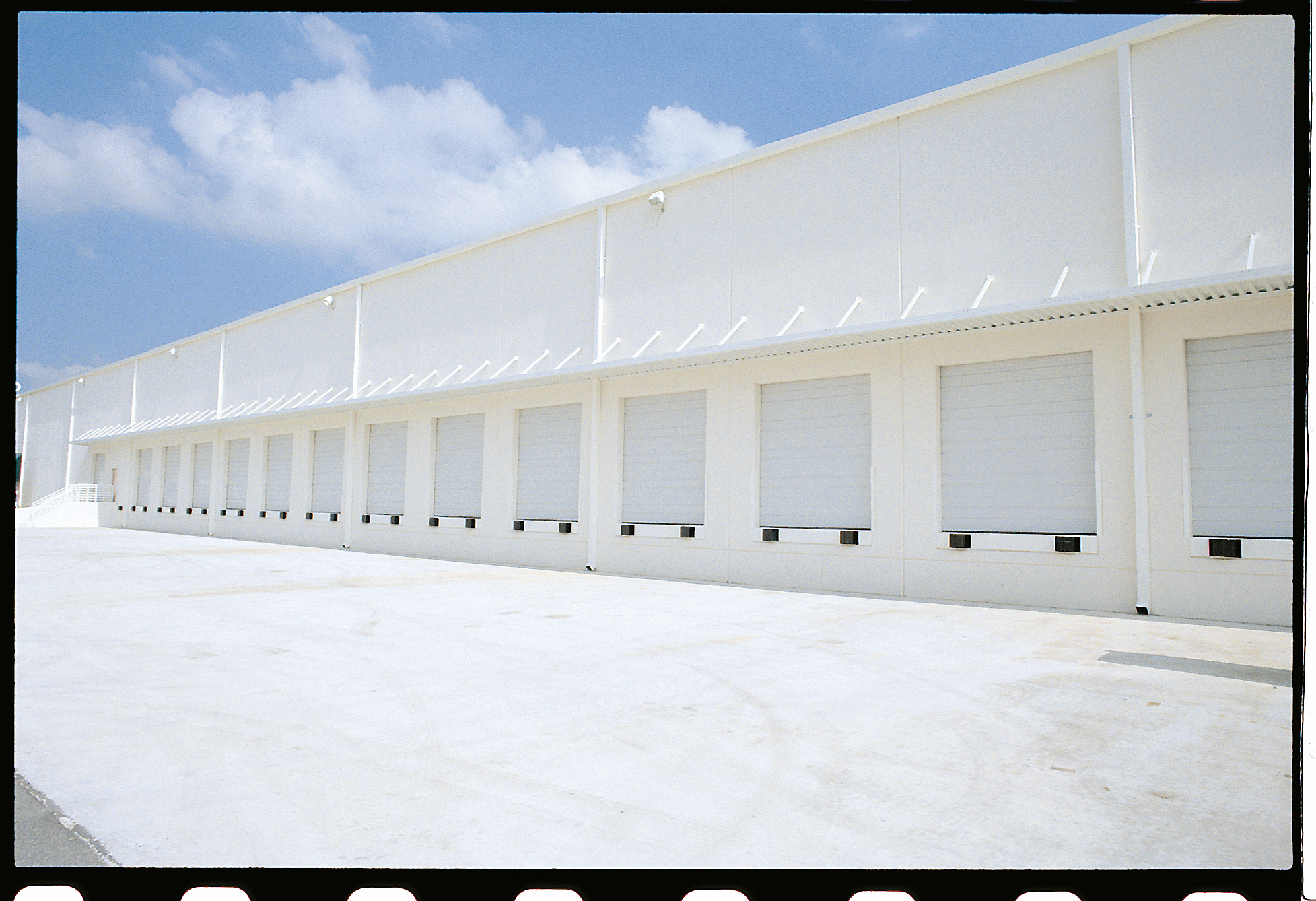 A long white commercial building with a row of multiple loading docks.