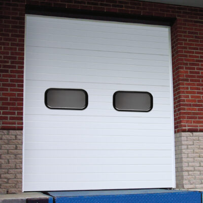 A white Amarr 2742 commercial steel sectional garage door with two small rectangular windows near the top.