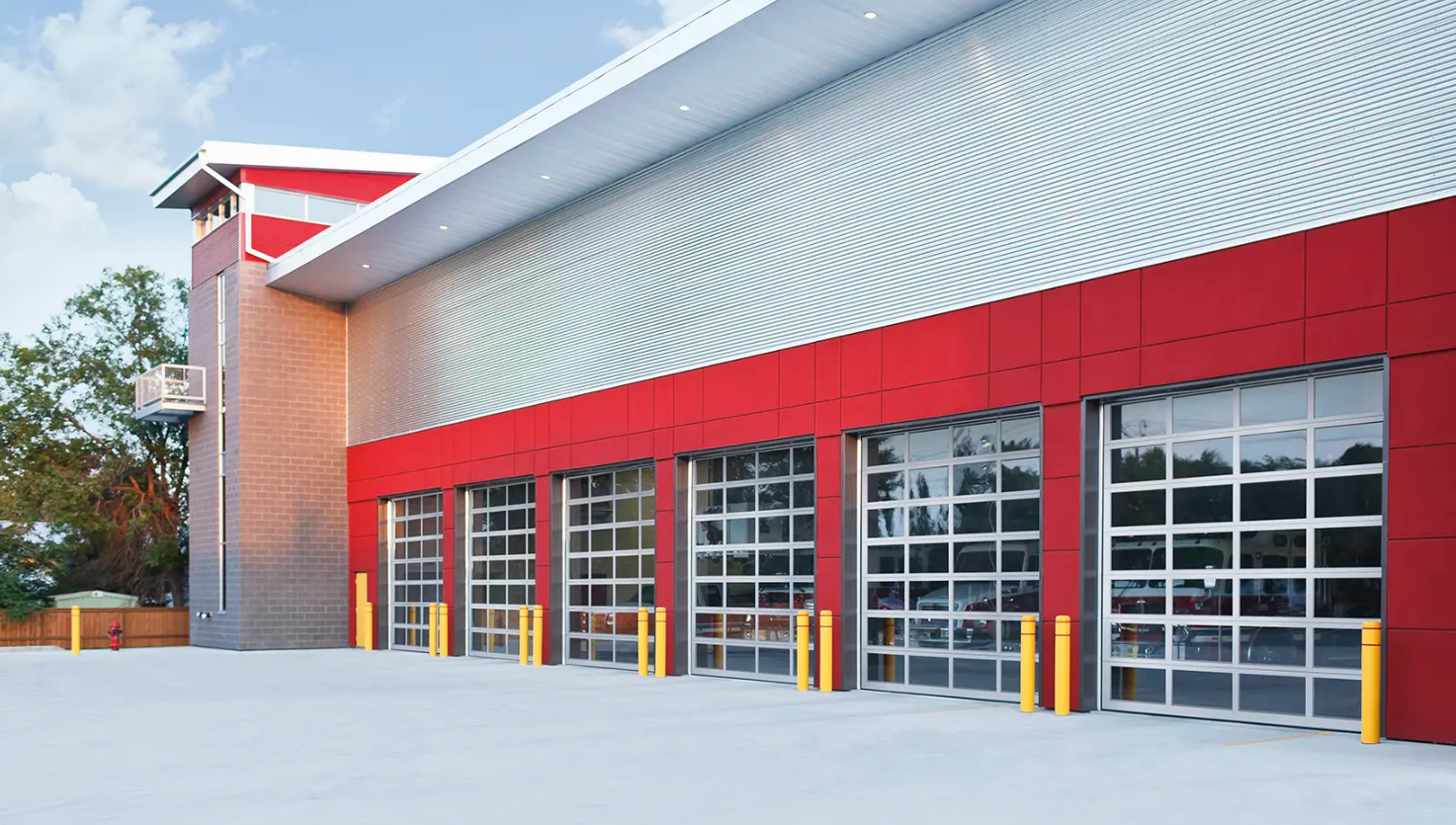 A modern fire station with multiple Clopay Architectural Series-Aluminum glass garage doors and red accents