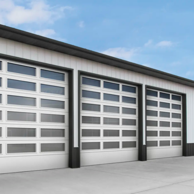 A modern metal building with three large commercial Clopay Architectural Series-Steel garage doors featuring multiple windows