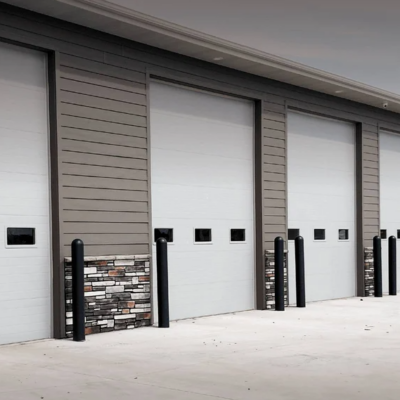 A large agricultural building with multiple white garage doors and green trim.