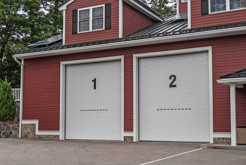 Two white CHI Rolling Service commercial garage doors on a red building.