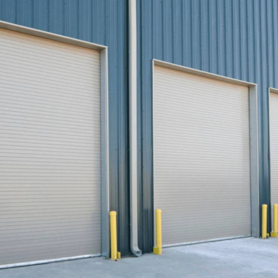 Three closed commercial roll-up doors in a row on a blue building.