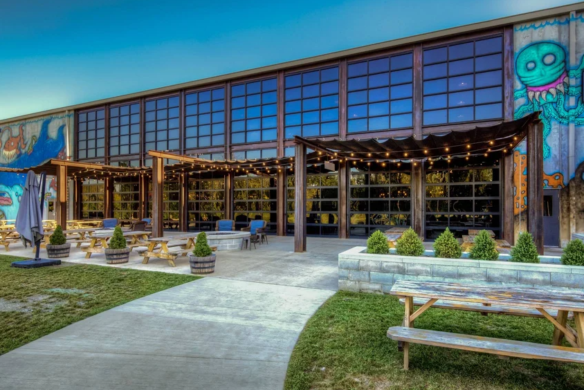 Outdoor patio with picnic tables in front of a large building with many windows