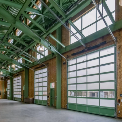 Interior of a fire station with large glass doors and green steel beams.