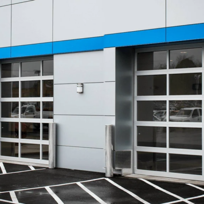 Two commercial glass garage doors with aluminum frames on a modern building exterior.