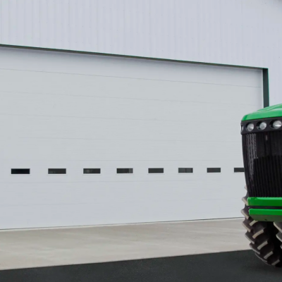 White commercial Clopay Energy Series garage door with windows, a green tractor parked in front