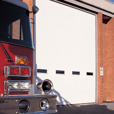 A red fire truck parked in front of a white Clopay Energy Series garage door at a fire station