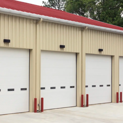 A row of white commercial Clopay Energy Series with Intellicore garage doors on a beige building with a red roof