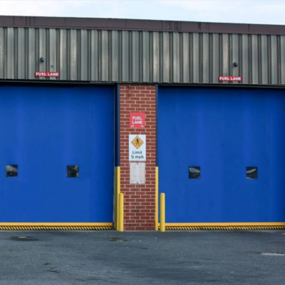 Two large blue industrial doors with yellow borders and warning signs.