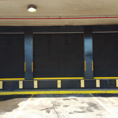 Three black loading dock doors with yellow safety markings.