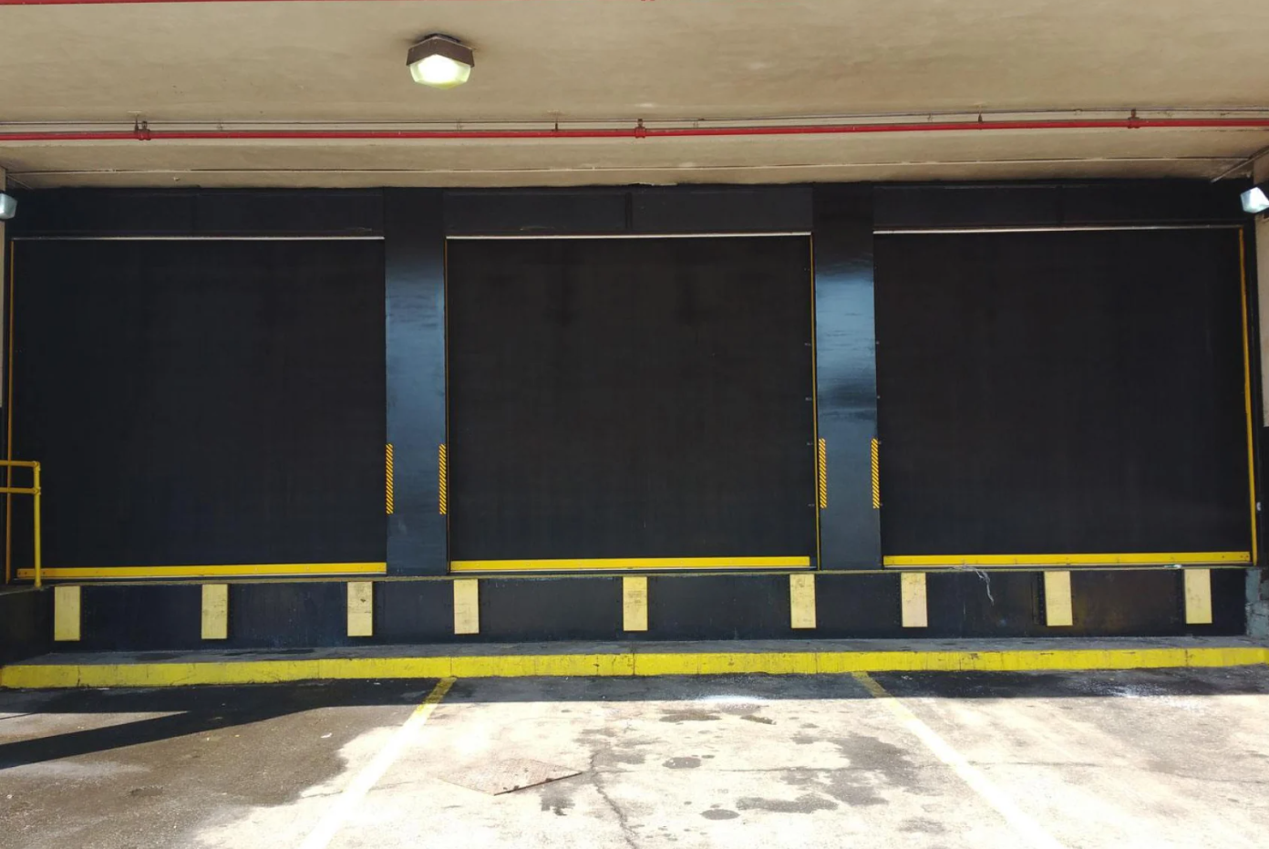 Three black loading dock doors with yellow safety markings.