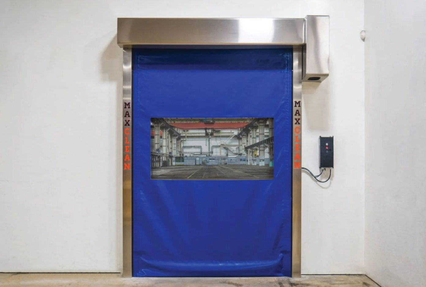 A blue MaxClean high-speed industrial door with a vision panel showing a warehouse interior.