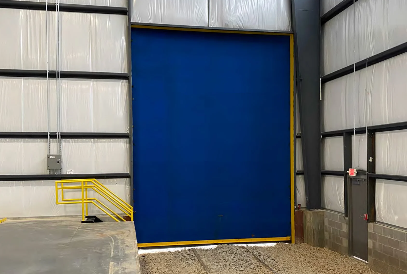 A large blue industrial door with a yellow frame, in a warehouse setting.