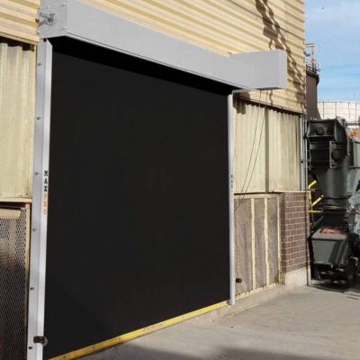 A large black industrial door with a gray frame on the exterior of a building.