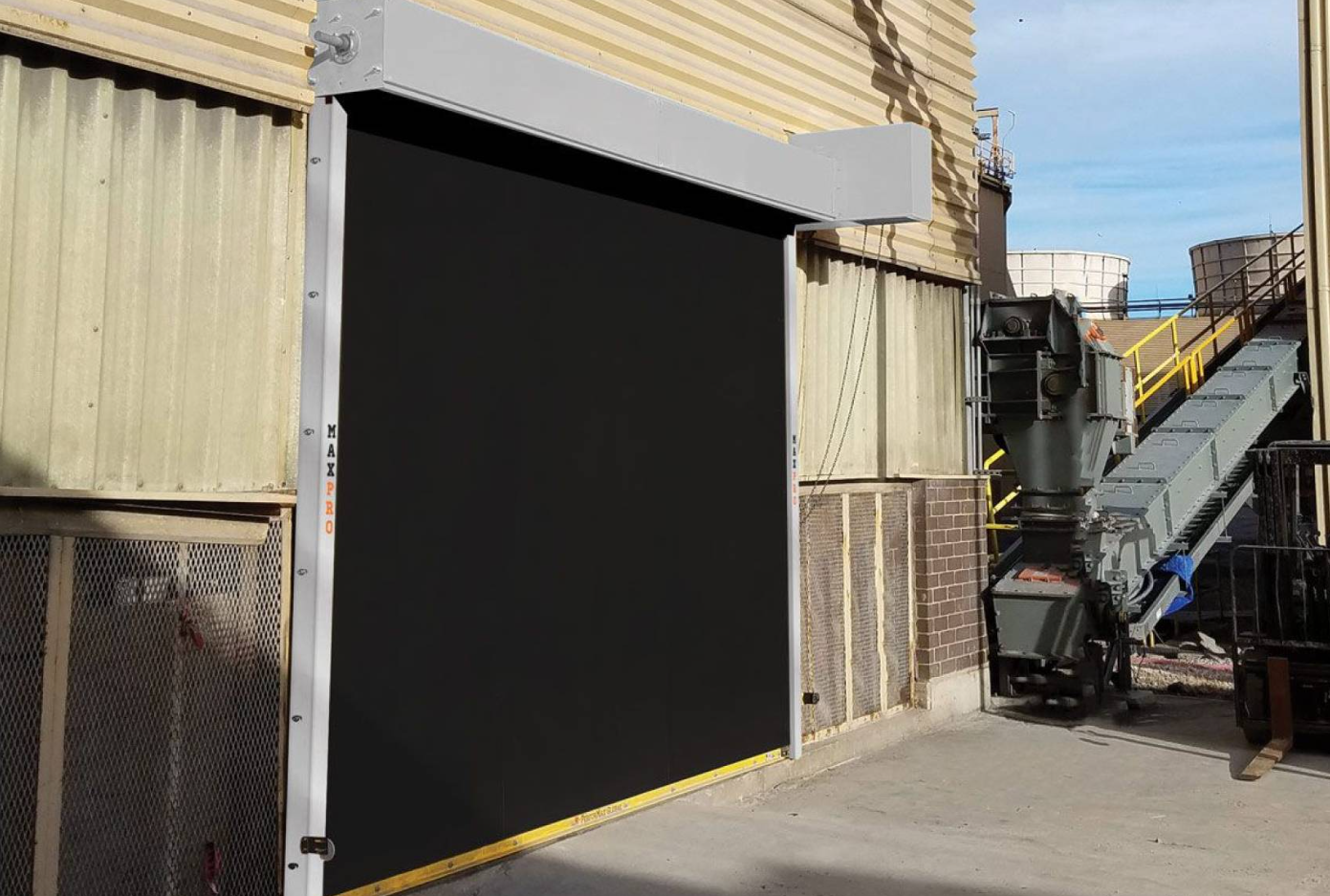 A large black industrial door with a gray frame on the exterior of a building.