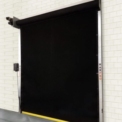 A black MaxPro roll-up door installed on a white brick wall.