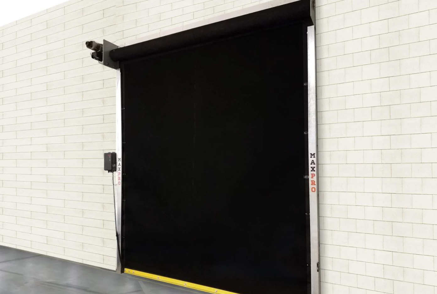 A black MaxPro roll-up door installed on a white brick wall.