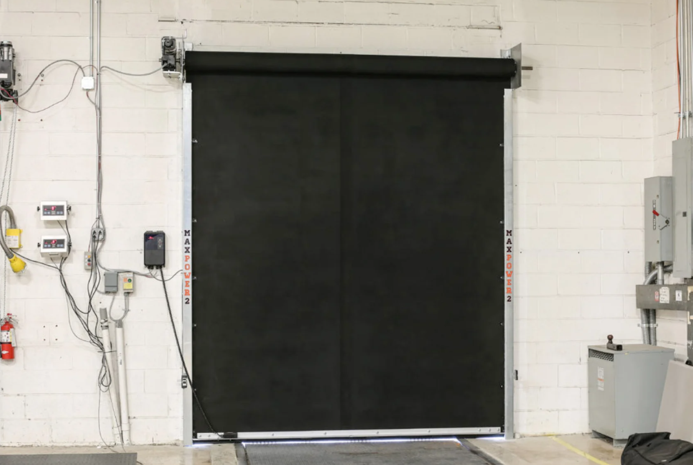 A black MaxPro industrial door with a metal frame installed on a white wall.