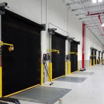 A row of several black high-speed industrial doors in a warehouse setting.