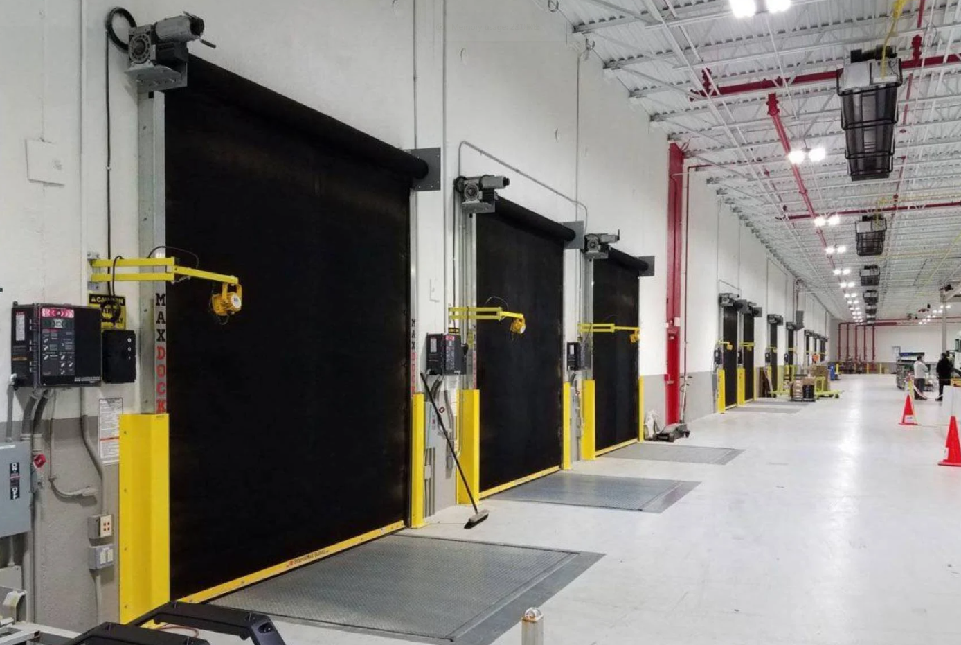 A row of several black high-speed industrial doors in a warehouse setting.