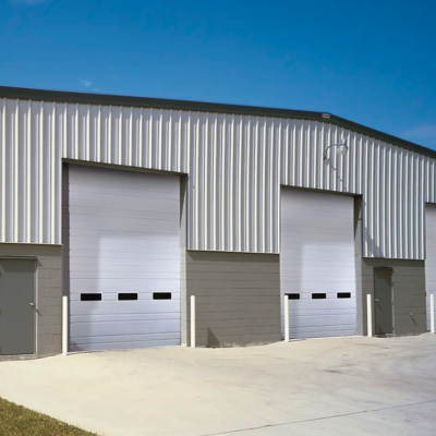 Metal industrial building with three large white Clopay Industrial Series garage doors