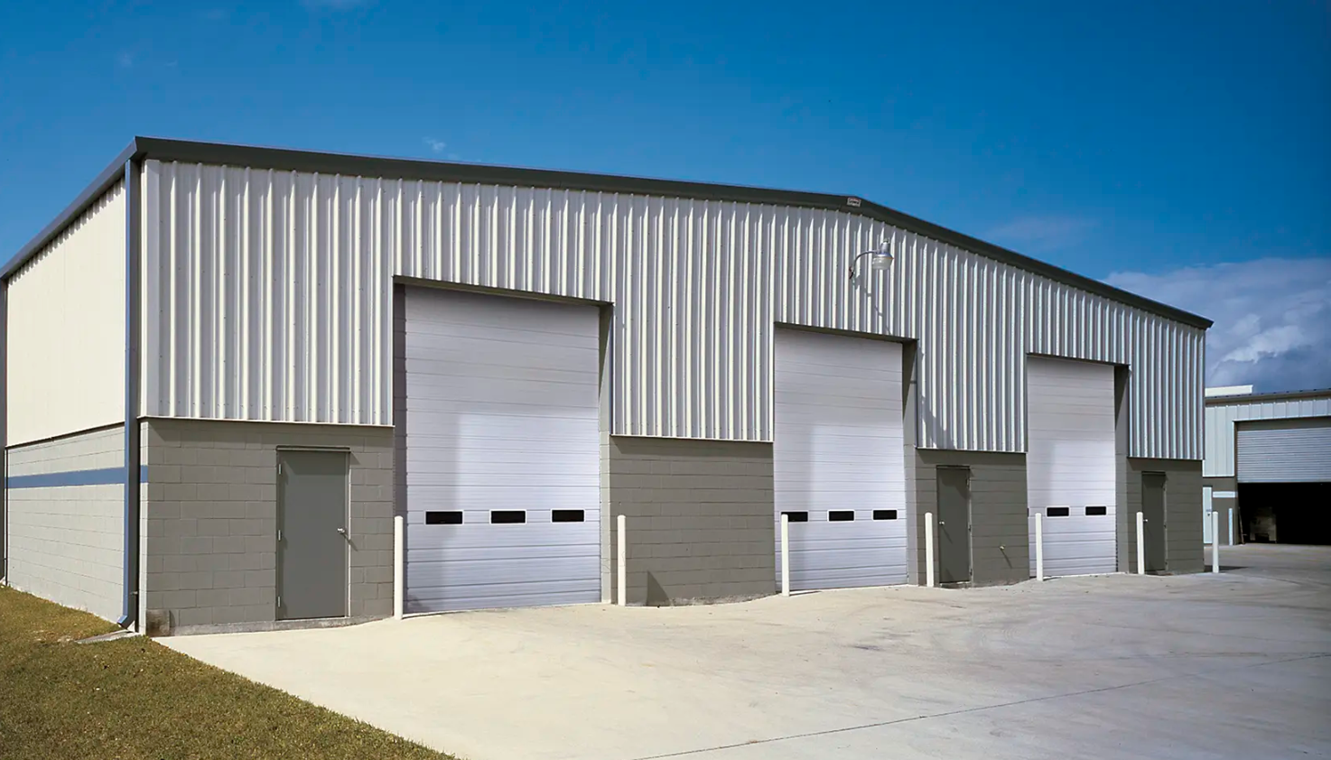 Metal industrial building with three large white Clopay Industrial Series garage doors