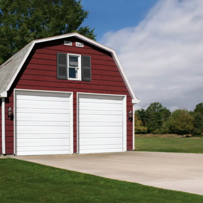 Red barn with white Clopay Industrial Series garage doors and a green lawn