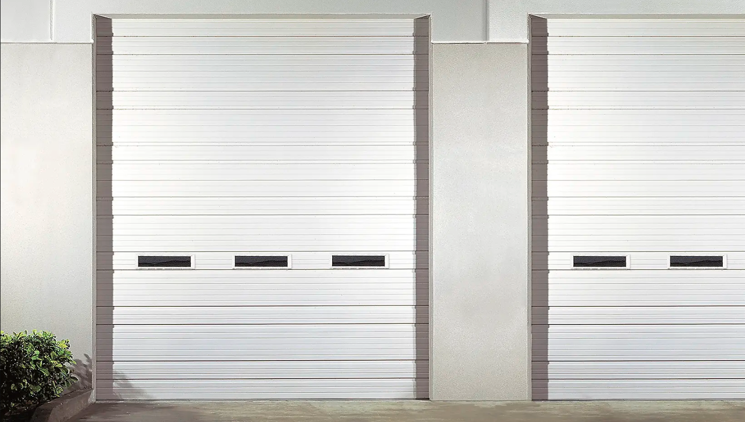 A white Clopay Industrial Series garage door with horizontal grooves and a row of small windows