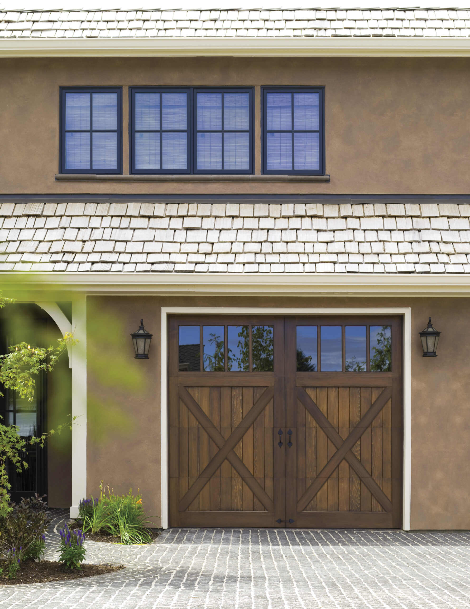 Rustic wooden garage door with cross-brace design and upper glass windows, set against a stucco home exterior.