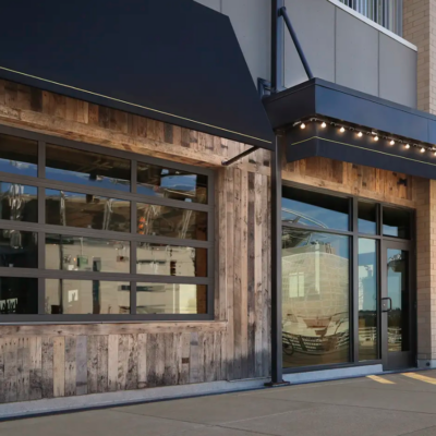 A restaurant exterior with a Clopay VertiStack Clear Door with rustic wood accents, and a black awning