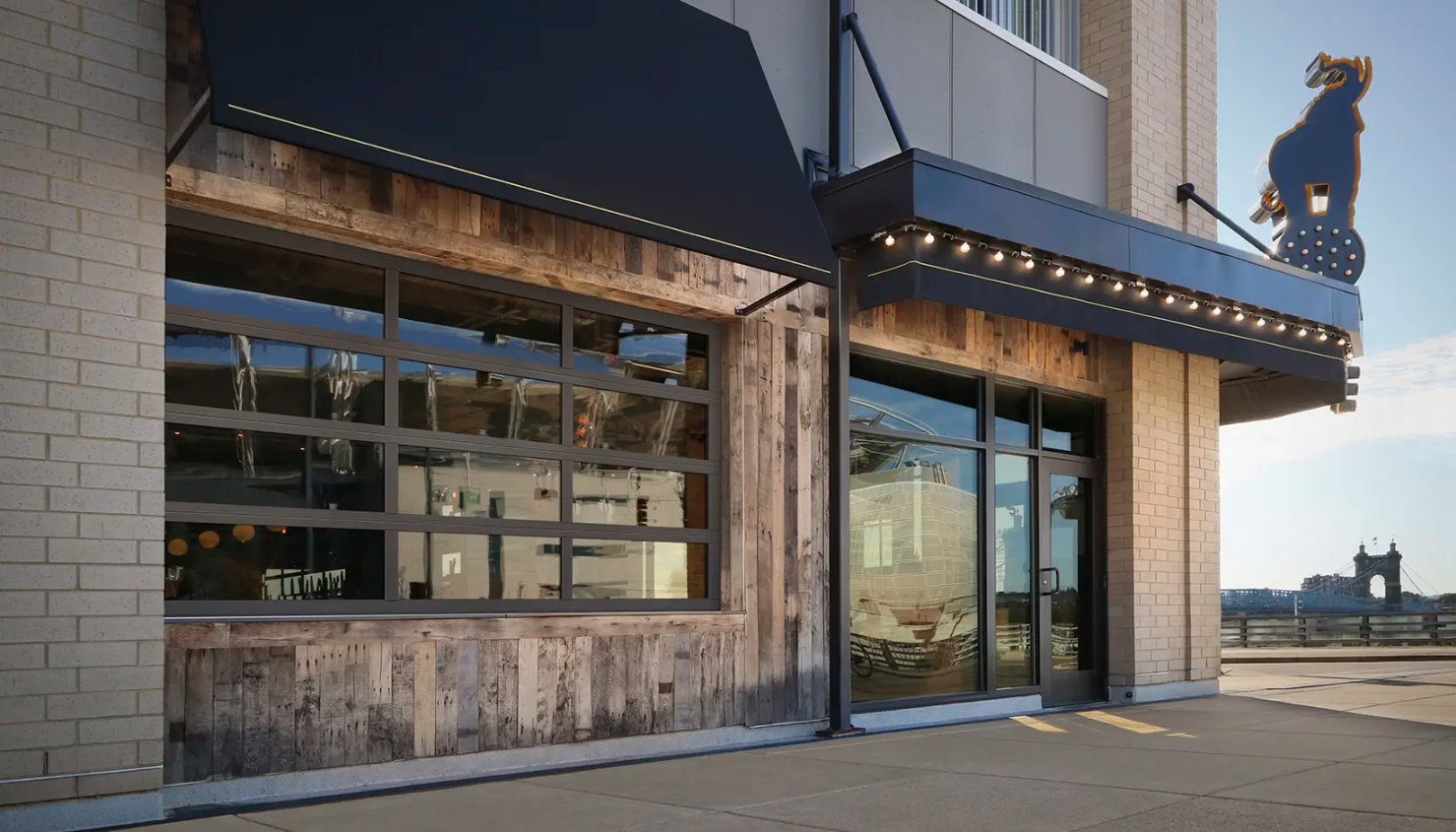 A restaurant exterior with a Clopay VertiStack Clear Door with rustic wood accents, and a black awning