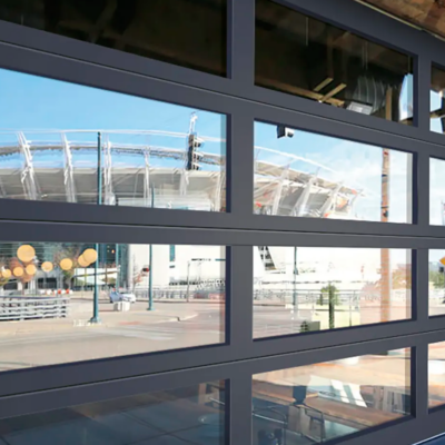 A commercial Clopay VertiStack Clear Door reflecting a cityscape with a stadium and clear blue sky