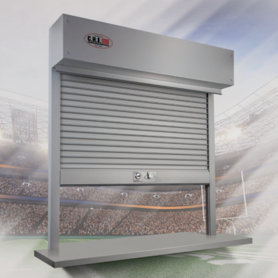 A stainless steel CHI roll-up security shutter with a control box on top, set against a stadium backdrop.